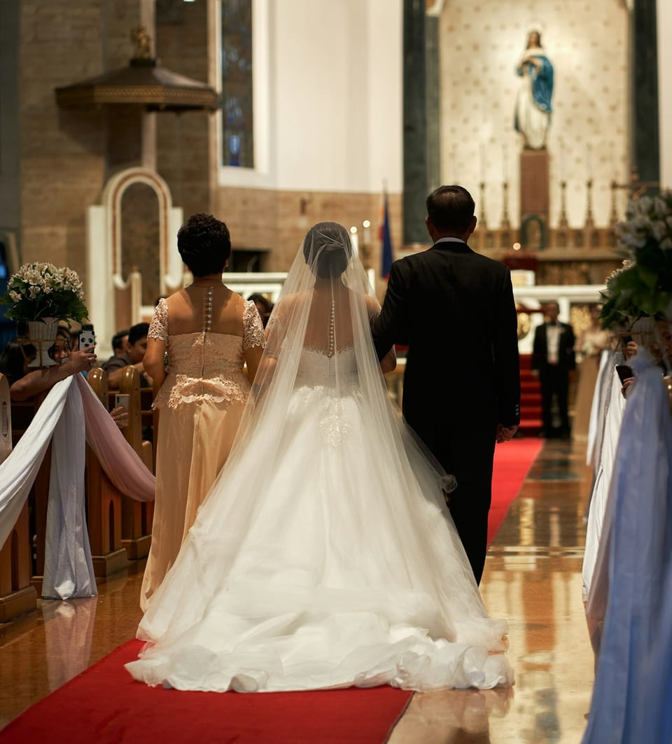 A bride is escorted down the aisle of a large impressive church